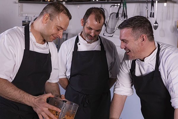 three chefs in aprons cooking together
